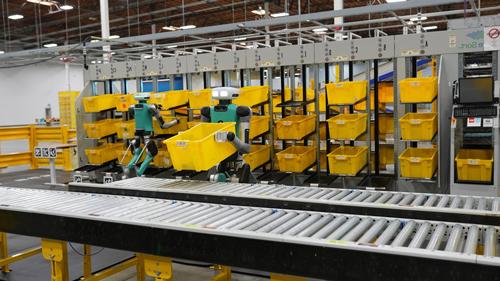 robot picking up yellow bins in a warehouse